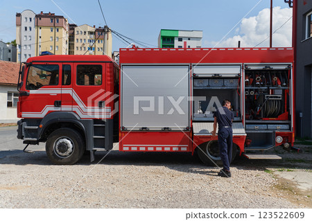 A dedicated firefighter preparing a modern firetruck for deployment to hazardous fire-stricken areas, demonstrating readiness and commitment to emergency response 123522609