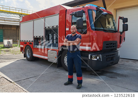 Confident firefighter stands with crossed arms, exuding resilience and preparedness, ready to respond to emergencies alongside a modern fire truck, showcasing the heroism and strength of the fire Confident firefighter stands with crossed arms, exuding resilience and preparedness, ready to respond to emergencies alongside a modern fire truck, showcasing the heroism and strength of the fire 123522618
