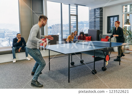 Business colleagues take a break from work to enjoy a game of table tennis, fostering teamwork and camaraderie in the workplace 123522621