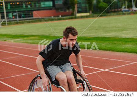 A person athlete with disability in a wheelchair racing on an outdoor track. 123522654