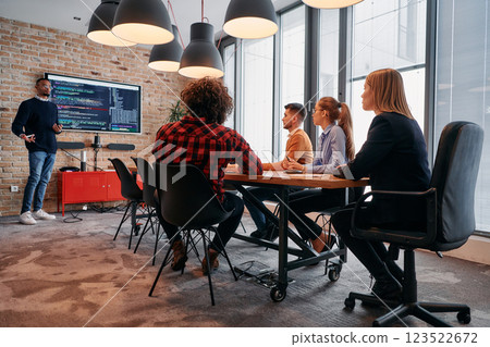 African-American businessman leads a meeting, passionately presenting a business plan to his attentive team, fostering collaboration and strategic thinking 123522672