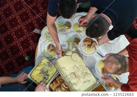 Top view of people serving food at a Mosque a communal meal during Ramadan before breaking the fast on Iftar dinner. Warm festive atmosphere celebrating Ramadan Karim and Eid, the Islamic holy month 123522683