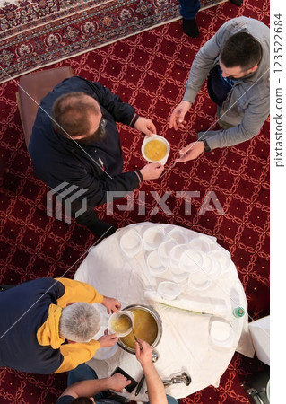 Top view of people serving food at a Mosque a communal meal during Ramadan before breaking the fast on Iftar dinner. Warm festive atmosphere celebrating Ramadan Karim and Eid, the Islamic holy month 123522684