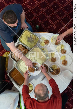 Top view of people serving food at a Mosque a communal meal during Ramadan before breaking the fast on Iftar dinner. Warm festive atmosphere celebrating Ramadan Karim and Eid, the Islamic holy month 123522687