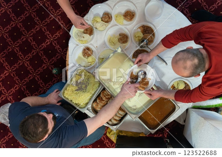 Top view of people serving food at a Mosque a communal meal during Ramadan before breaking the fast on Iftar dinner. Warm festive atmosphere celebrating Ramadan Karim and Eid, the Islamic holy month 123522688