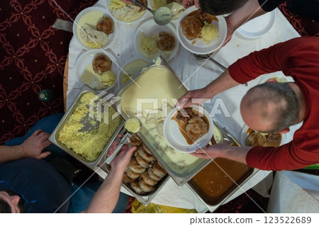Top view of people serving food at a Mosque a communal meal during Ramadan before breaking the fast on Iftar dinner. Warm festive atmosphere celebrating Ramadan Karim and Eid, the Islamic holy month 123522689