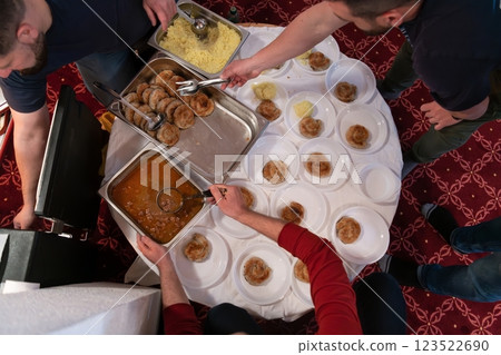 Top view of people serving food at a Mosque a communal meal during Ramadan before breaking the fast on Iftar dinner. Warm festive atmosphere celebrating Ramadan Karim and Eid, the Islamic holy month 123522690