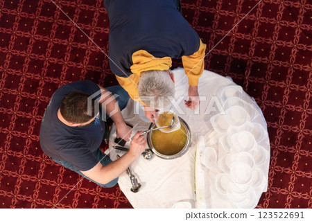 Top view of people serving food at a Mosque a communal meal during Ramadan before breaking the fast on Iftar dinner. Warm festive atmosphere celebrating Ramadan Karim and Eid, the Islamic holy month 123522691