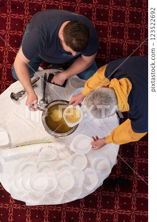 Top view of people serving food at a Mosque a communal meal during Ramadan before breaking the fast on Iftar dinner. Warm festive atmosphere celebrating Ramadan Karim and Eid, the Islamic holy month 123522692