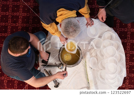 Top view of people serving food at a Mosque a communal meal during Ramadan before breaking the fast on Iftar dinner. Warm festive atmosphere celebrating Ramadan Karim and Eid, the Islamic holy month 123522697