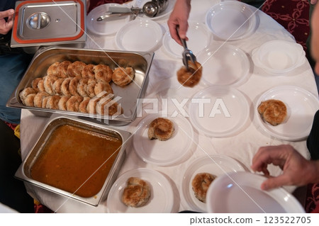 Top view of people serving food at a Mosque a communal meal during Ramadan before breaking the fast on Iftar dinner. Warm festive atmosphere celebrating Ramadan Karim and Eid, the Islamic holy month Top view of people serving food at a Mosque a communal meal during Ramadan before breaking the fast on Iftar dinner. Warm festive atmosphere celebrating Ramadan Karim and Eid, the Islamic holy month 123522705