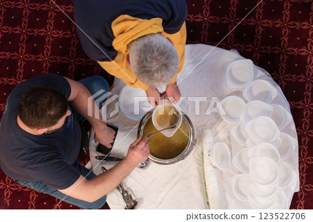 Top view of people serving food at a Mosque a communal meal during Ramadan before breaking the fast on Iftar dinner. Warm festive atmosphere celebrating Ramadan Karim and Eid, the Islamic holy month 123522706