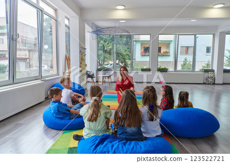 Reading time in an elementary school or kindergarten, a teacher reading a book to children in an elementary school or kindergarten. The concept of pre-school education. Selective focus 123522721
