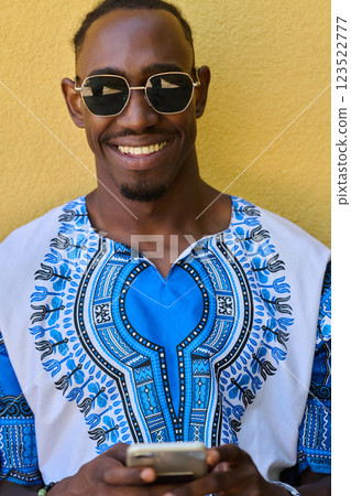 African American Teenager in Traditional Sudanese Attire Engaged with Smartphone African American Teenager in Traditional Sudanese Attire Engaged with Smartphone 123522777