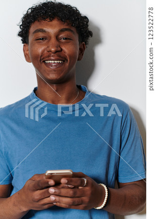African American teenager engages with his smartphone against a pristine white background, encapsulating the essence of contemporary digital connectivity and youth culture 123522778