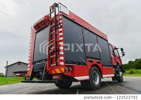 In this captivating scene, a state-of-the-art firetruck, equipped with advanced rescue technology, stands ready with its skilled firefighting team, prepared to intervene and respond rapidly to 123522791