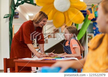 Creative kids during an art class in a daycare center or elementary school classroom drawing with female teacher. Creative kids during an art class in a daycare center or elementary school classroom drawing with female teacher. 123522979