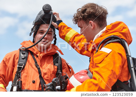 A unified team of firefighters, adorned in their uniforms, engages in a heartfelt celebration marked by triumphant salutes and cheers, embodying the joy and gratitude following the successful 123523059
