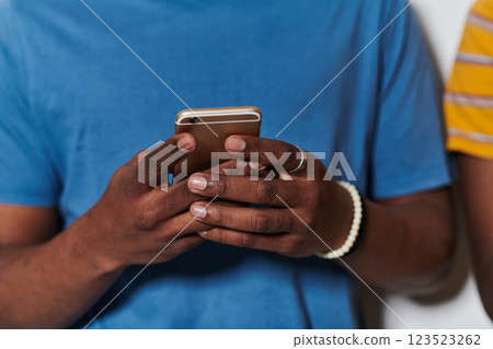 African American teenager engages with his smartphone against a pristine white background, encapsulating the essence of contemporary digital connectivity and youth culture African American teenager engages with his smartphone against a pristine white background, encapsulating the essence of contemporary digital connectivity and youth culture 123523262