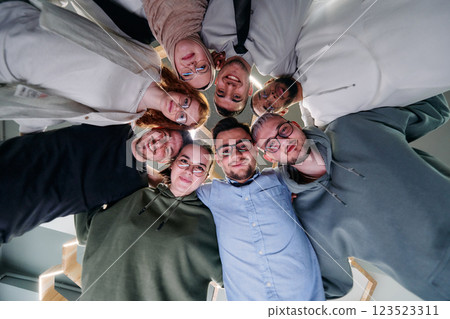 In a modern office, a group of young business professionals is captured in a warm and embracing hug, reflecting the spirit of unity, collaboration, and shared success in their dynamic workplace. 123523311