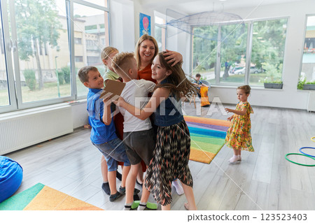 A child hugging a teacher in a modern kindergarten A child hugging a teacher in a modern kindergarten 123523403