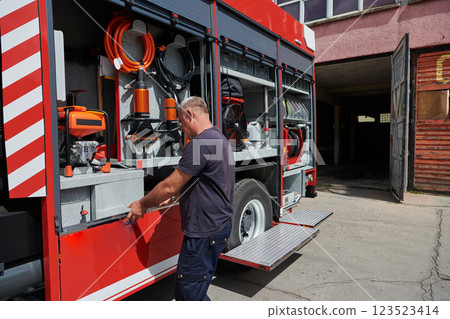 A dedicated firefighter preparing a modern firetruck for deployment to hazardous fire-stricken areas, demonstrating readiness and commitment to emergency response A dedicated firefighter preparing a modern firetruck for deployment to hazardous fire-stricken areas, demonstrating readiness and commitment to emergency response 123523414