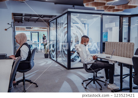 In a modern office setting, an African American businessman and his Muslim colleague, wearing a hijab, engage in collaborative discussions, tackling various business tasks and solving problems 123523421