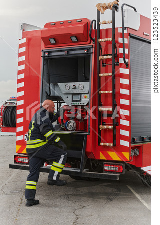 A firefighter meticulously prepares a modern firetruck for a mission to evacuate and respond to dangerous situations, showcasing the utmost dedication to safety and readiness in the face of a fire A firefighter meticulously prepares a modern firetruck for a mission to evacuate and respond to dangerous situations, showcasing the utmost dedication to safety and readiness in the face of a fire 123523439
