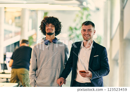 In a modern startup office setting, a business director and a young African American entrepreneur sit surrounded by their colleagues, embodying diversity and teamwork in the corporate world. 123523459