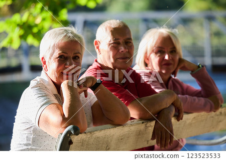 A group of elderly individuals, including a senior man and two older women, sits in a park on a sunny autumn day, embodying the concept of healthy aging through companionship, relaxation, and outdoor 123523533