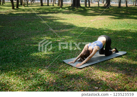 Young sporty woman practicing yoga on mat in a park 123523559