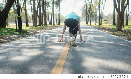 Sporty woman crouching down in starting position ready for sprint Sporty woman crouching down in starting position ready for sprint 123523574