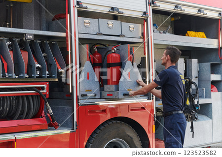 A dedicated firefighter preparing a modern firetruck for deployment to hazardous fire-stricken areas, demonstrating readiness and commitment to emergency response 123523582