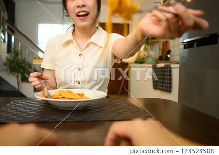 Smiling young woman feeding spaghetti to her boyfriend at the dinner table Smiling young woman feeding spaghetti to her boyfriend at the dinner table 123523588