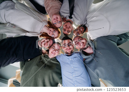 In a modern office, a group of young business professionals is captured in a warm and embracing hug, reflecting the spirit of unity, collaboration, and shared success in their dynamic workplace. 123523653