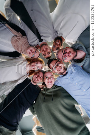 In a modern office, a group of young business professionals is captured in a warm and embracing hug, reflecting the spirit of unity, collaboration, and shared success in their dynamic workplace. 123523762
