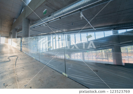 A captivating view of a modern business building under construction, showcasing its raw industrial interior with exposed steel beams and concrete walls bathed in the warm, golden hues of a sunset 123523769