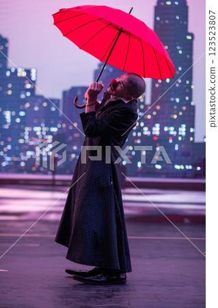 Mysterious Clown Performer with Red Umbrella in Urban Nightscape. 123523807