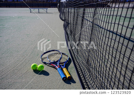 Racket and ball placed near the net on a tennis court 123523920