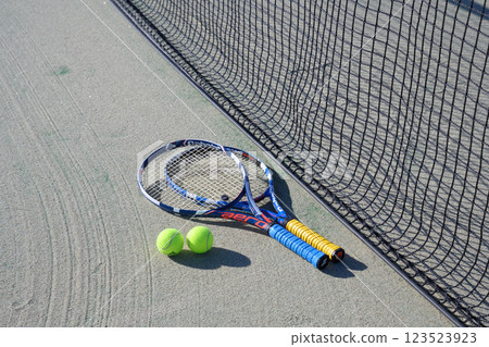 Racket and ball placed near the net on a tennis court 123523923