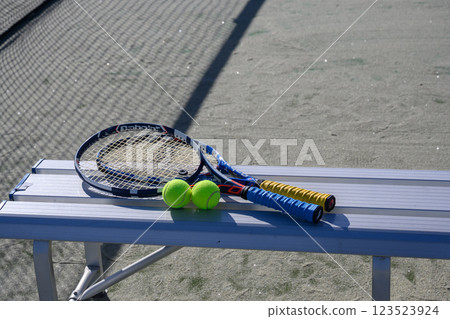 Racket and ball on a bench in a tennis court 123523924