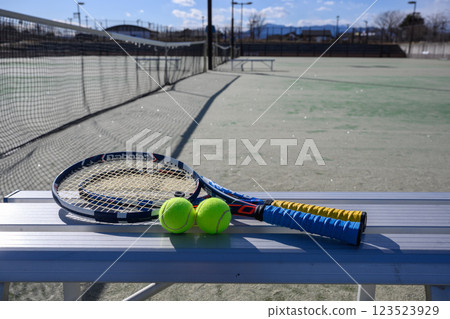 Racket and ball on a bench in a tennis court 123523929
