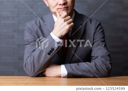 A middle-aged male businessman wearing a gray suit and worried 123524599