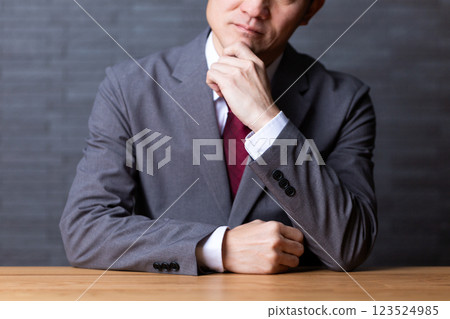 A middle-aged male businessman wearing a gray suit and worried A middle-aged male businessman wearing a gray suit and worried 123524985