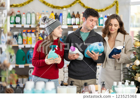 Couple man and woman with daughter choosing detergent and spray in decorated store 123525368
