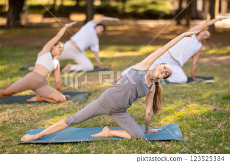 Woman participating in outdoor group yoga session in city park 123525384