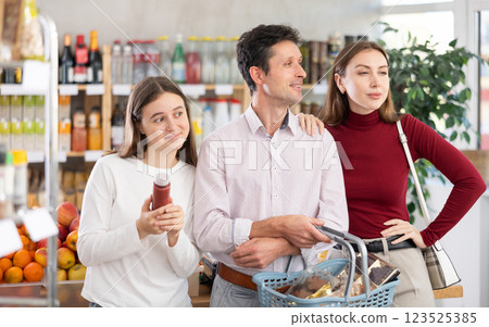 In store, family with purchases in hands looking for something on shelf of showcase 123525385