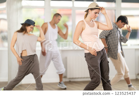 Group of energetic hip hop dancers focused on training while gathered together in spacious dance hall Group of energetic hip hop dancers focused on training while gathered together in spacious dance hall 123525437