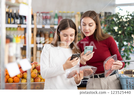 Mom and daughter scanning packages of hamburger patties Mom and daughter scanning packages of hamburger patties 123525440