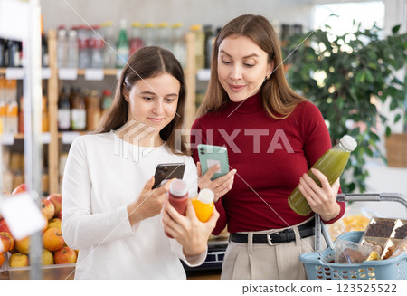 Teenage girl and her mother scanning QR on bottle of smoothie in supermarket 123525522